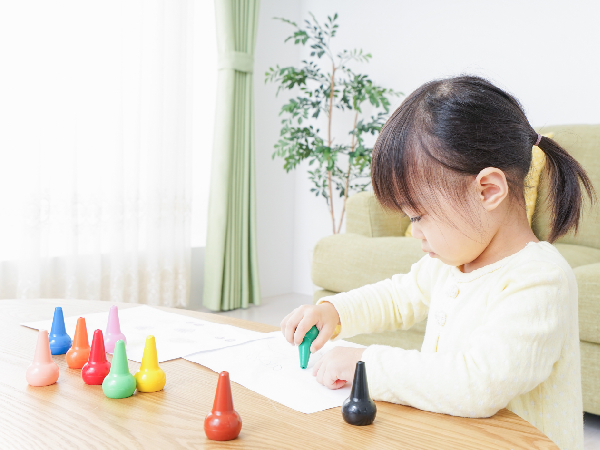 お絵描きをして遊ぶ小さい女の子の横顔の写真