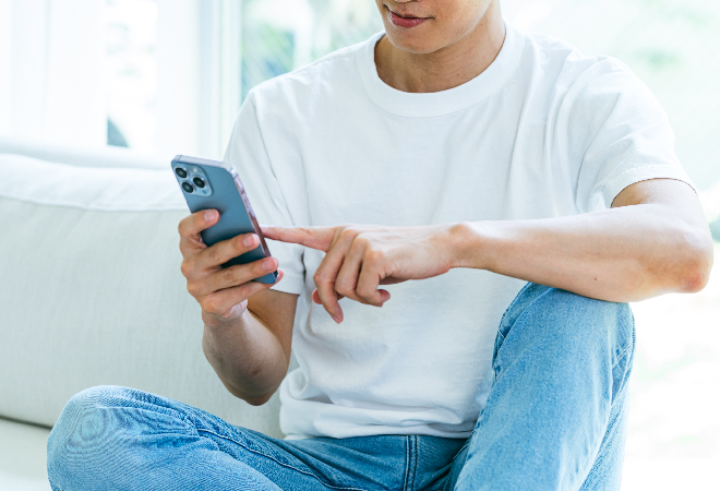 スマホを操作する若い男性の手元の写真。