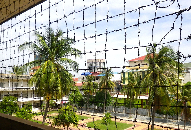 有刺鉄線越しに見える東南アジアの街並みの写真。