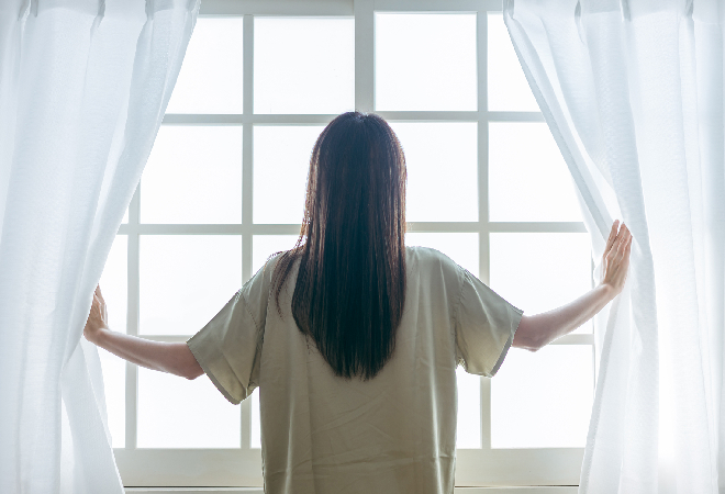 明るい光の中で窓をひらく女性の後ろ姿の写真、事件の解決への希望をにじませている。