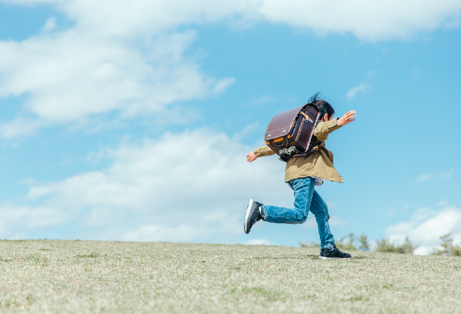 ランドセルを背負っている子どもがどこかに向かって走っている写真。