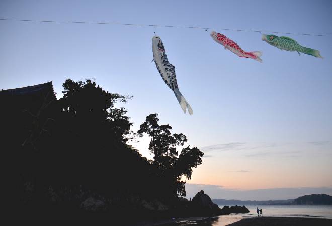 夕暮れに沈む実家とこいのぼりの写真、昔の思い出に影が落ちているイメージ。