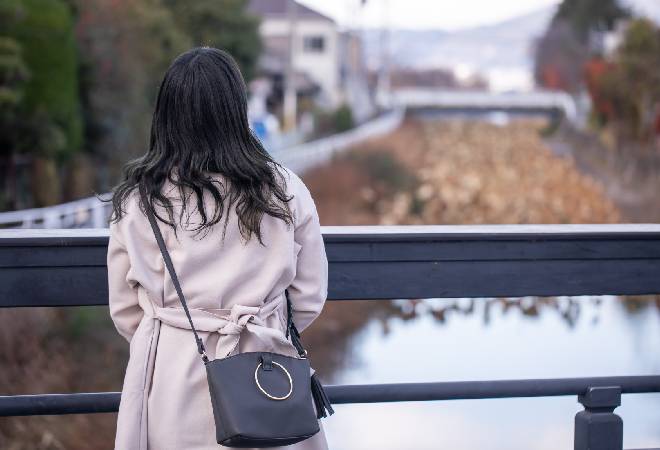 橋の上に立つ元カノのような女性の後ろ姿の写真。
