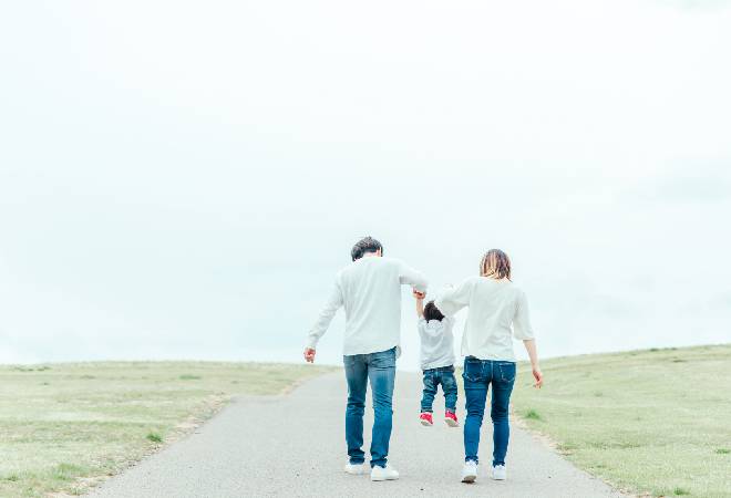 手をつないで歩く両親と子どもの後ろ姿の、少し寂しげな写真。