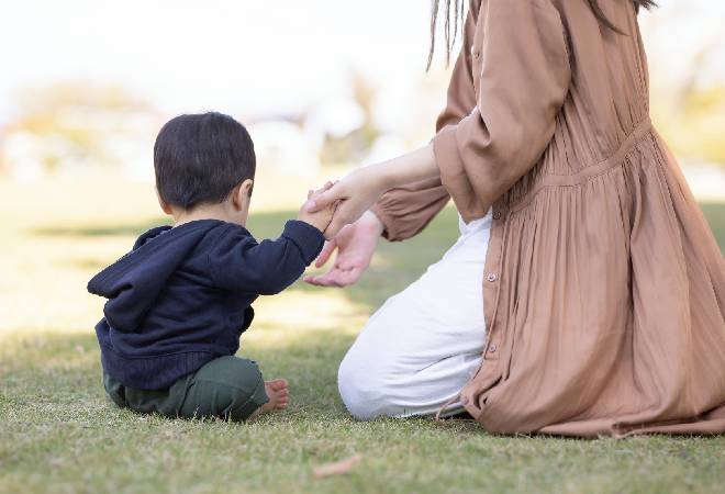 手をつないでいる母と幼い子供の写真。