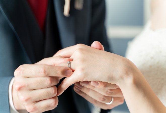 女性に結婚指輪をつけようとする男性の写真。